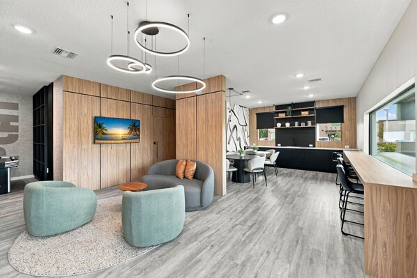 A modern living room with a sofa, ottoman, and a painting of a sunset. - Brand new townhouse in The Hub (Kissimmee)