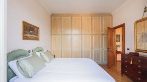 A bedroom with a bed, a dresser, a wardrobe, and a painting on the wall. - Bright and cozy apartment located in the heart of Rome, Vatican area.   (Roma)