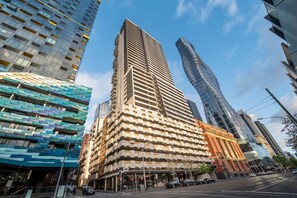 A modern high-rise building with a unique architectural design, featuring a grid-like facade and a prominent corner entrance. - Chic Apartment by Southern Cross, FREE Parking (Melbourne)