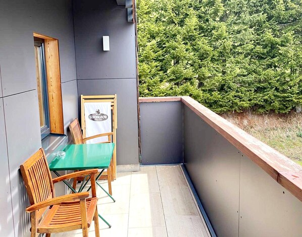Un balcon avec une table et des chaises, un cadre photo en bois et une enseigne indiquant « CIDRE DE POMME STRONGBOW ».