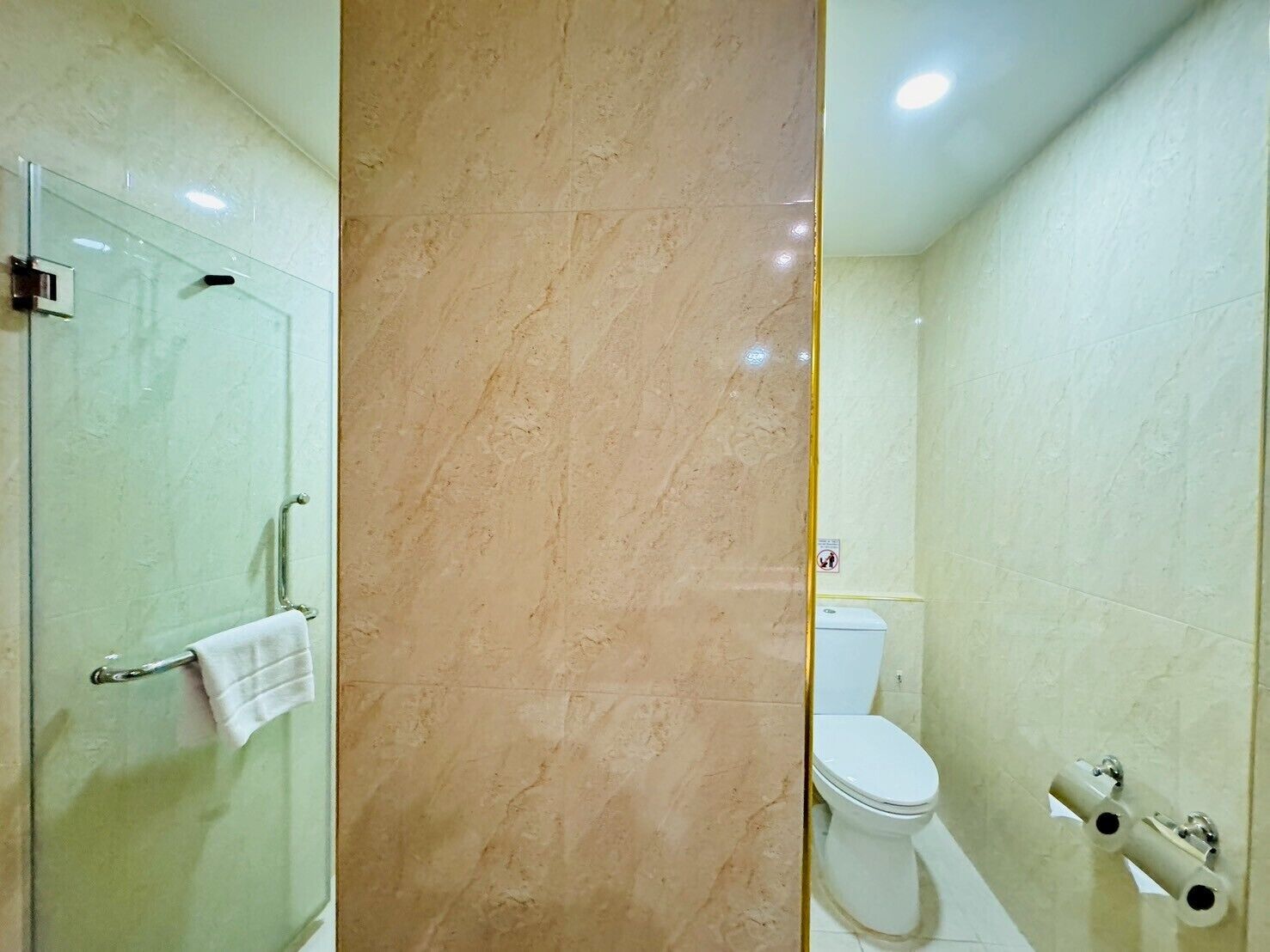 A bathroom with a glass shower enclosure, a toilet, and a bidet.