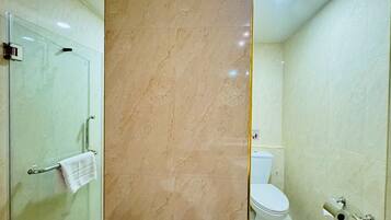 A bathroom with a glass shower enclosure, a toilet, and a bidet.