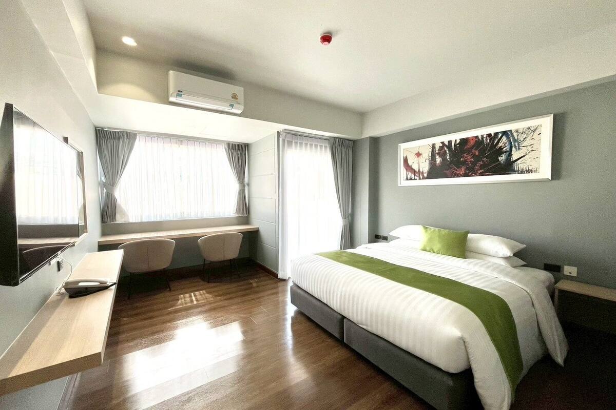 Une chambre d’hôtel avec un lit, un bureau, deux chaises, une télévision et un tableau au mur.