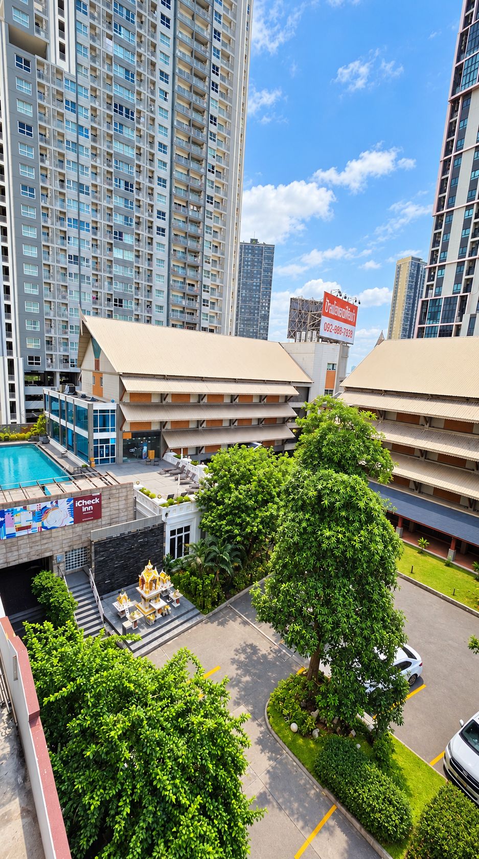 A multi-story hotel with a swimming pool, a restaurant, and a large tree in the courtyard.