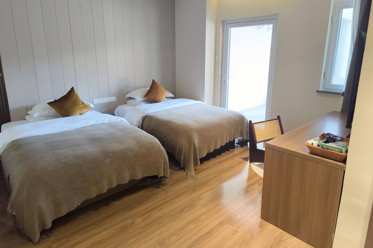 Ein Hotelzimmer mit zwei Betten, einem Holztisch und einem Fenster.