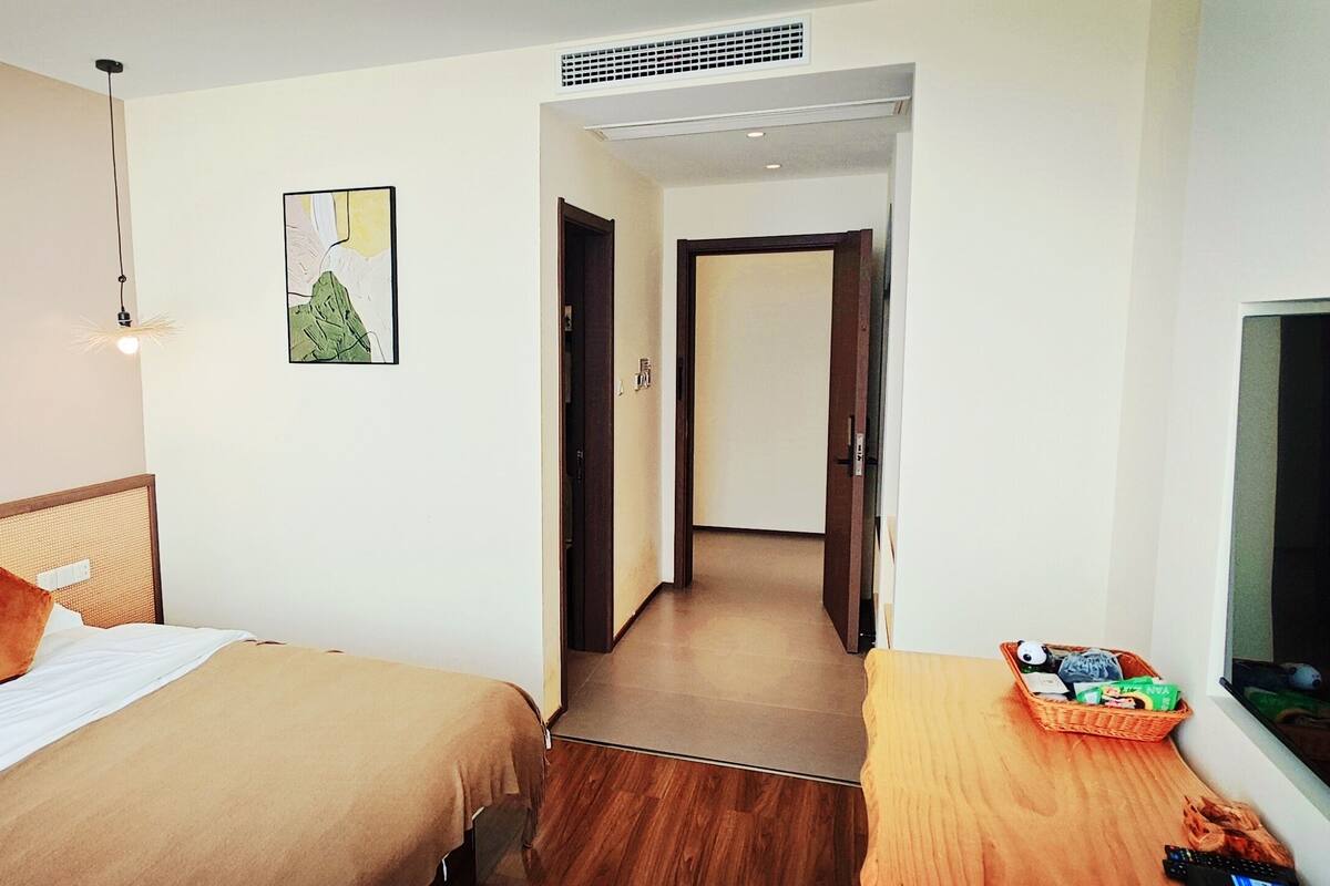 Ein Hotelzimmer mit zwei Betten, einem Fernseher, einem Nachttisch aus Holz und einem gerahmten Bild an der Wand.
