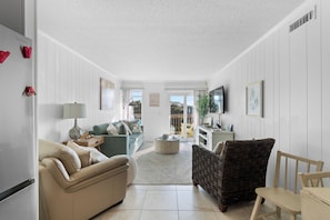 Ein Wohnzimmer mit Sofa, Sessel, Couchtisch und Fernseher.