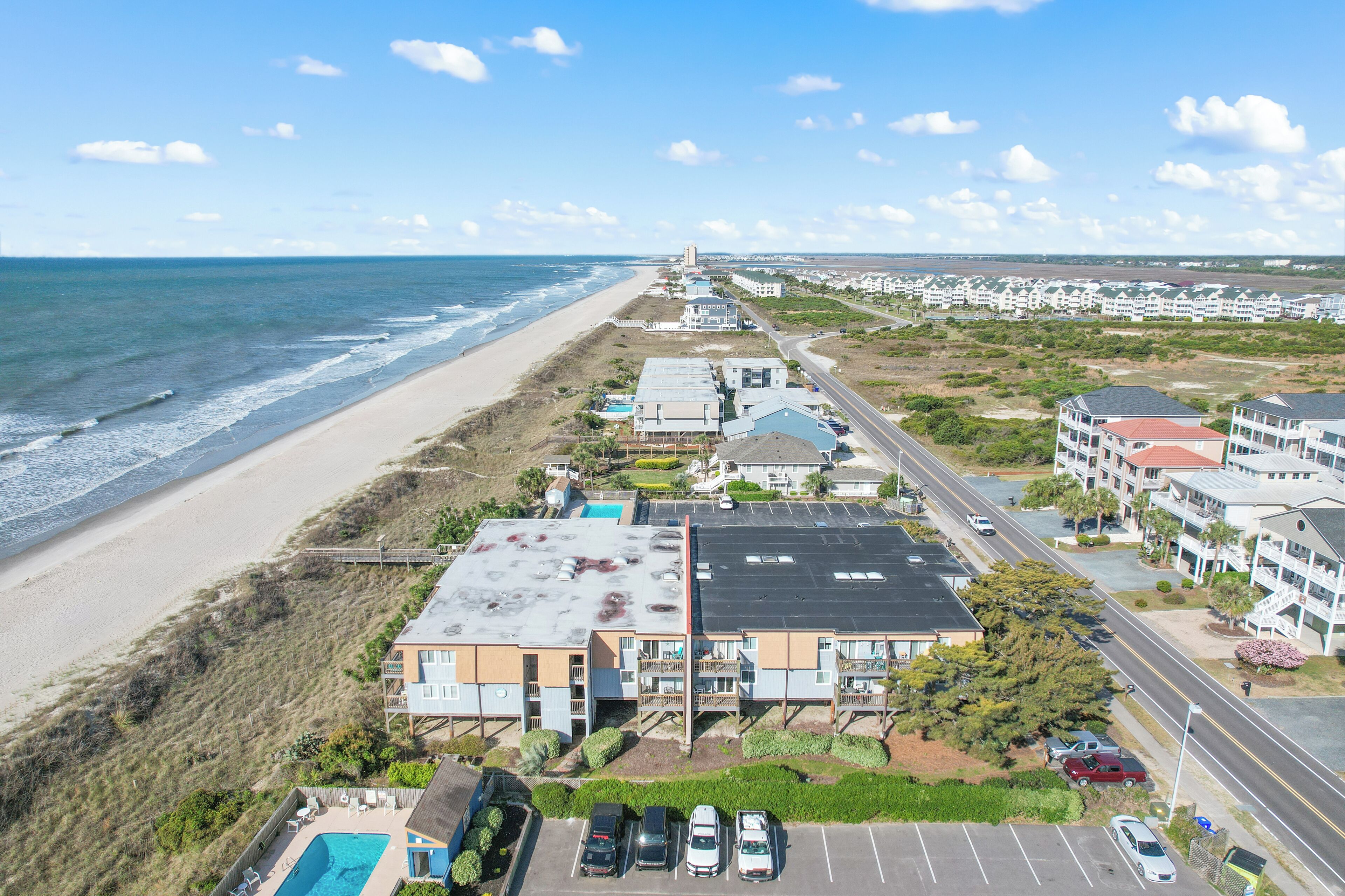Ein Hotel an der Küste mit mehreren Gebäuden, einem Parkplatz und Blick auf den Strand.