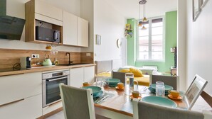 Een moderne keuken met een eethoek, voorzien van een houten aanrecht, roestvrijstalen apparatuur en een heldergroene wand.