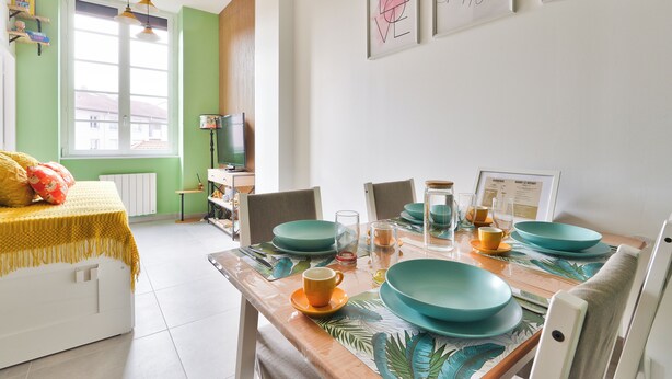 Een eetgedeelte met blauwgroene borden, een gele tafelkleed en een bed met een gele deken.