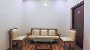 A room with a sofa, two chairs, a coffee table, and a door. - SRJ Thaneesh Residency (Ootacamund)