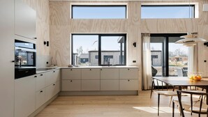 A modern kitchen with a large window, wooden cabinetry, and a dining area with a table and chairs.