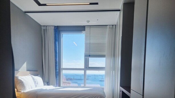 A modern hotel room with a large bed, a glass coffee table, and a view of the sea. - The Bayment Residence (Busan)