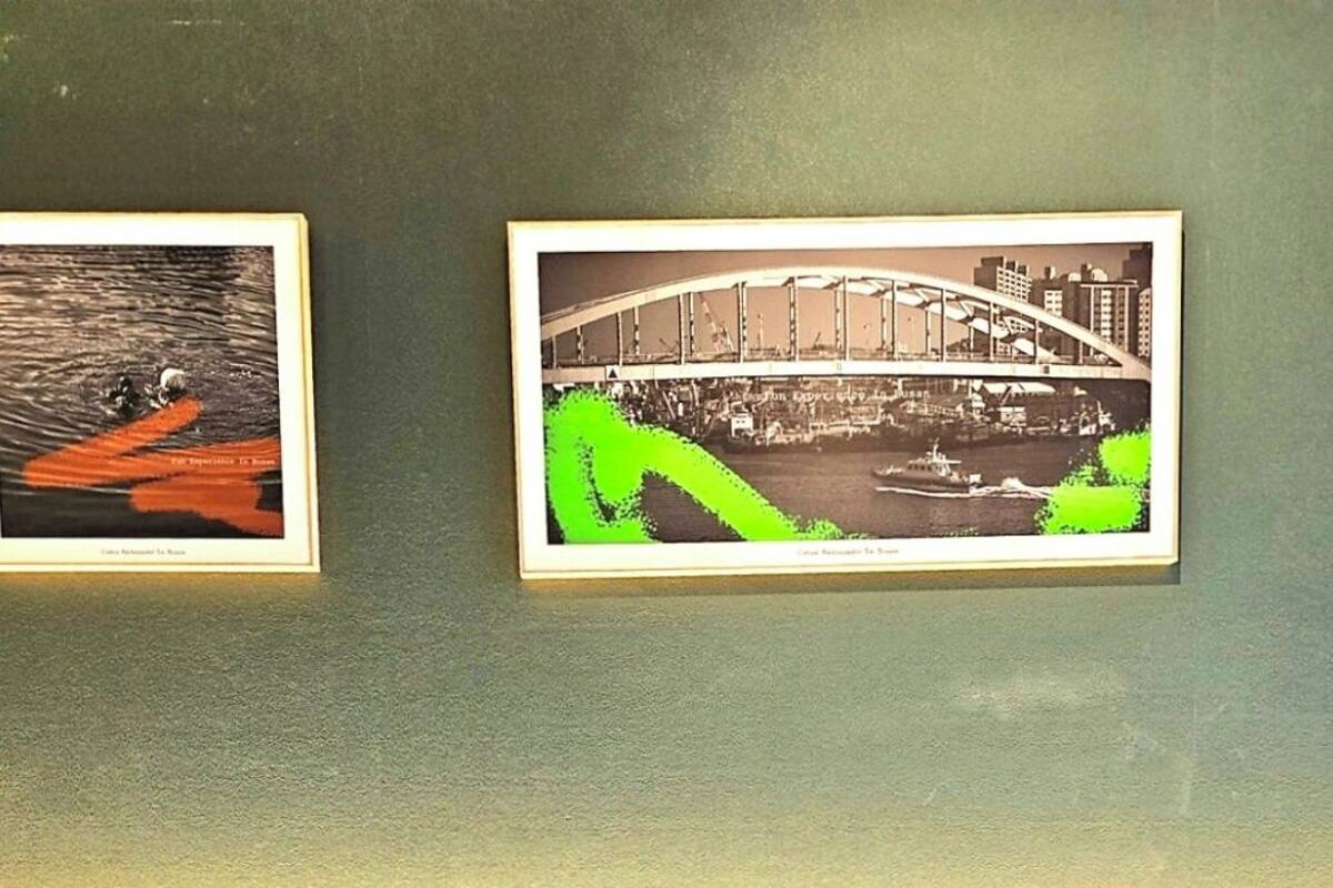 A hotel room with two beds, a wooden headboard, and two framed pictures on the wall.