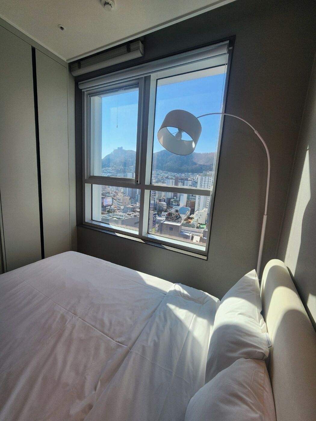 Une chambre avec une grande fenêtre, un lit et une lampe moderne.