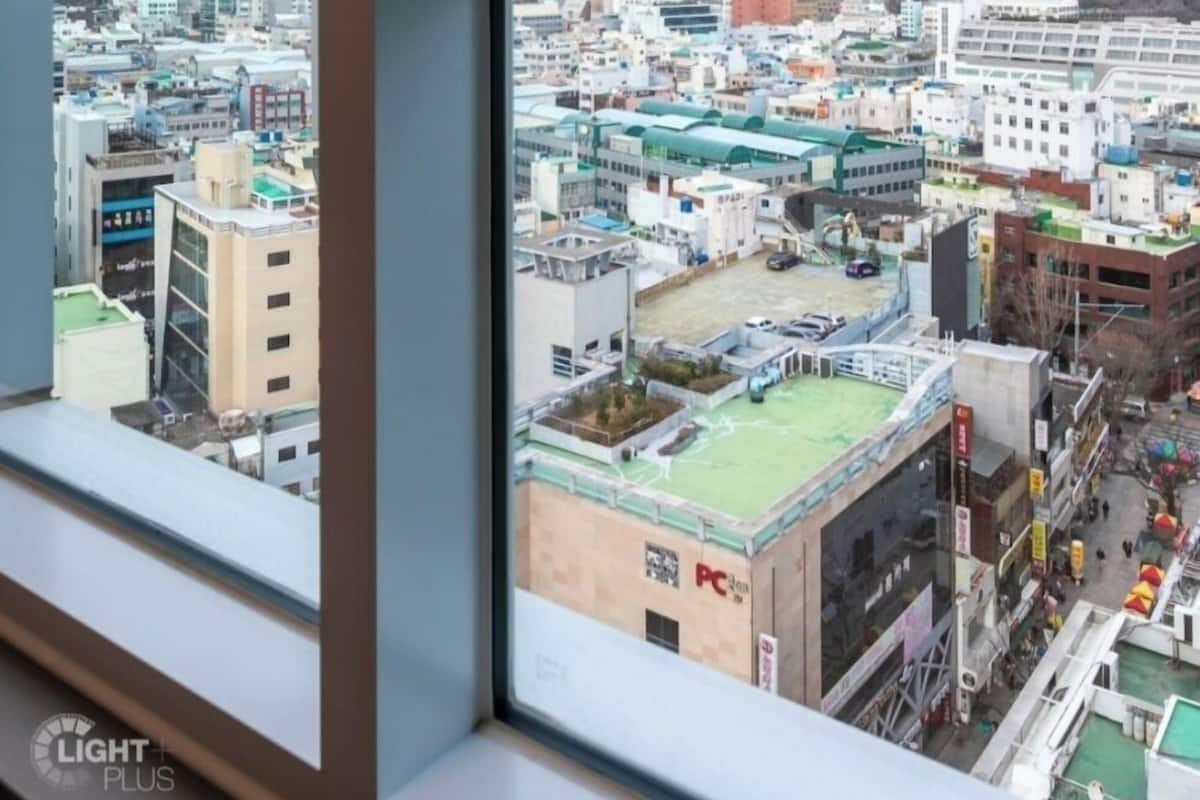 A view from a window overlooking a cityscape with buildings and a tower.