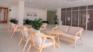 Una hall moderna con arredi in legno, piante in vaso e ampie finestre.