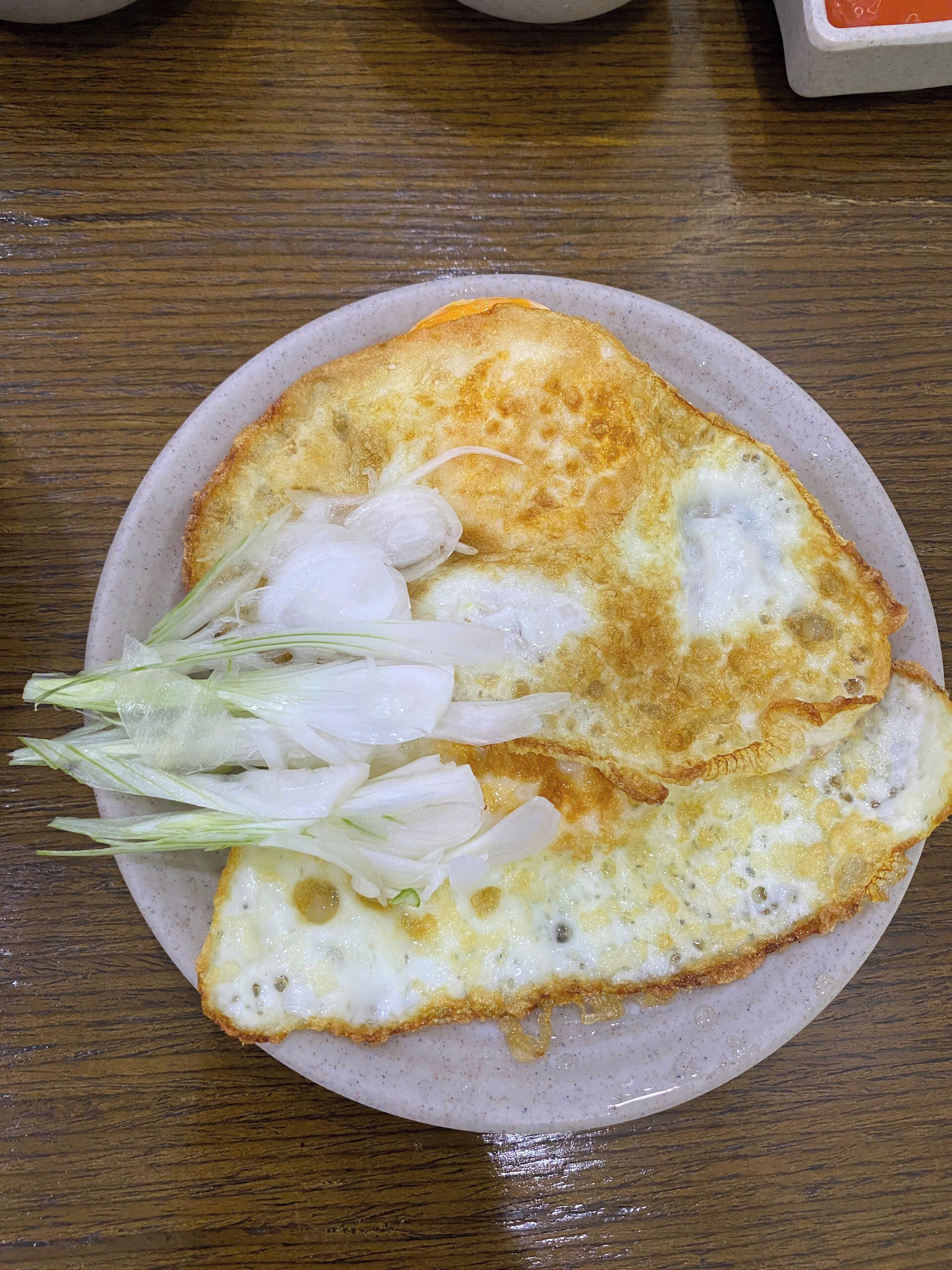 Une assiette avec un œuf au plat et des radis coupés en tranches, le tout présenté sur une assiette ronde en céramique.