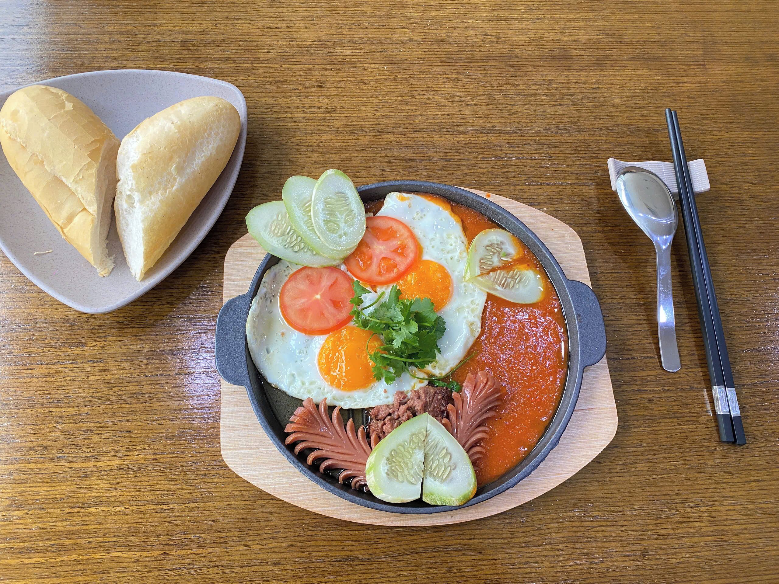 A meal with eggs, tomatoes, and cucumbers on a wooden table.