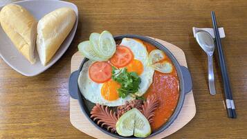 A meal with eggs, tomatoes, and cucumbers on a wooden table.
