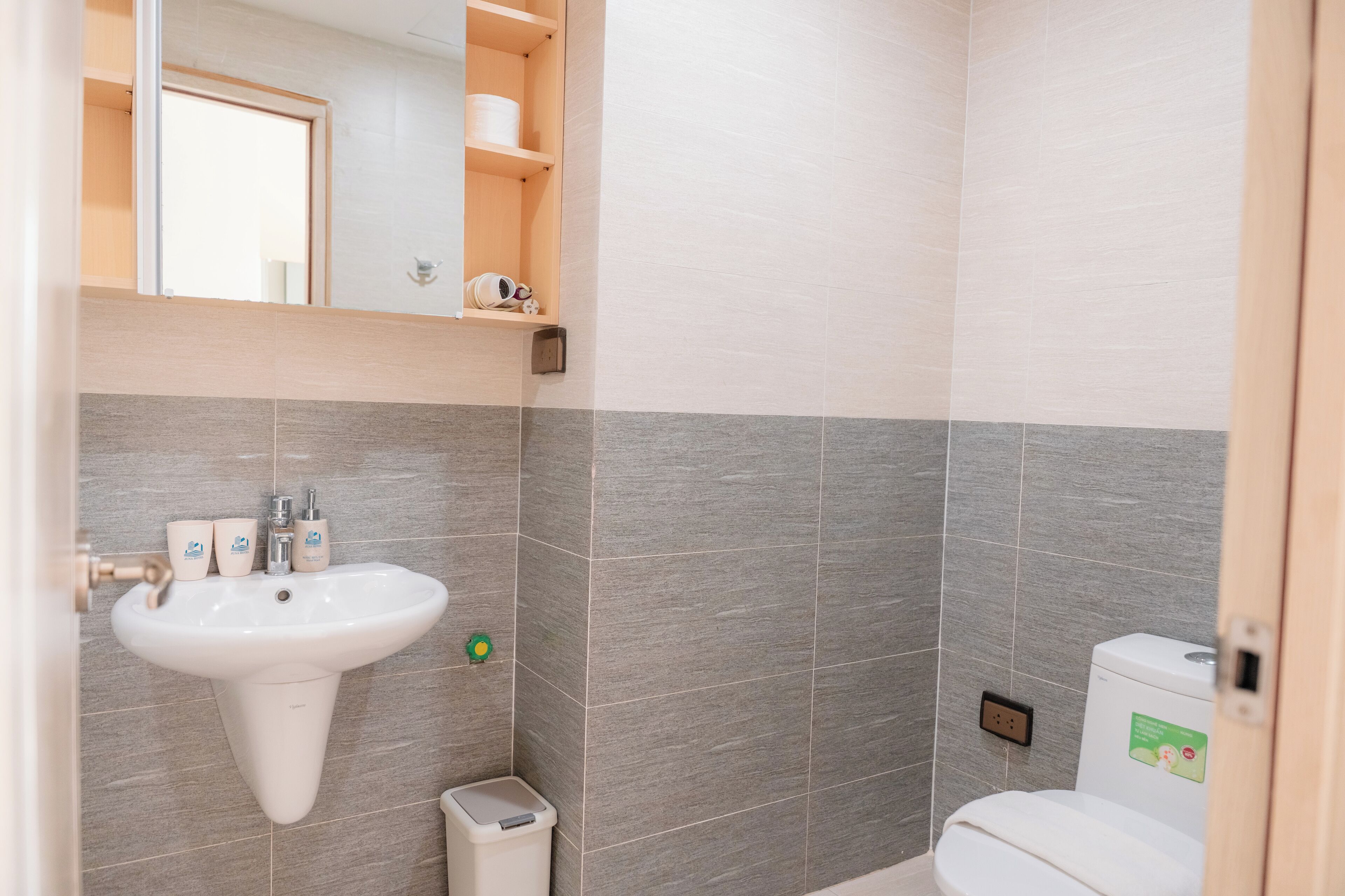 Un baño con lavamanos, inodoro y un pequeño cubo de basura.