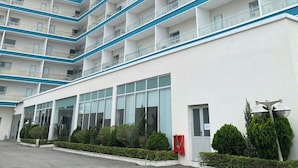 Un hotel a più piani con un cartello ben visibile "JUNAHOTEL", ampie finestre e un parcheggio.