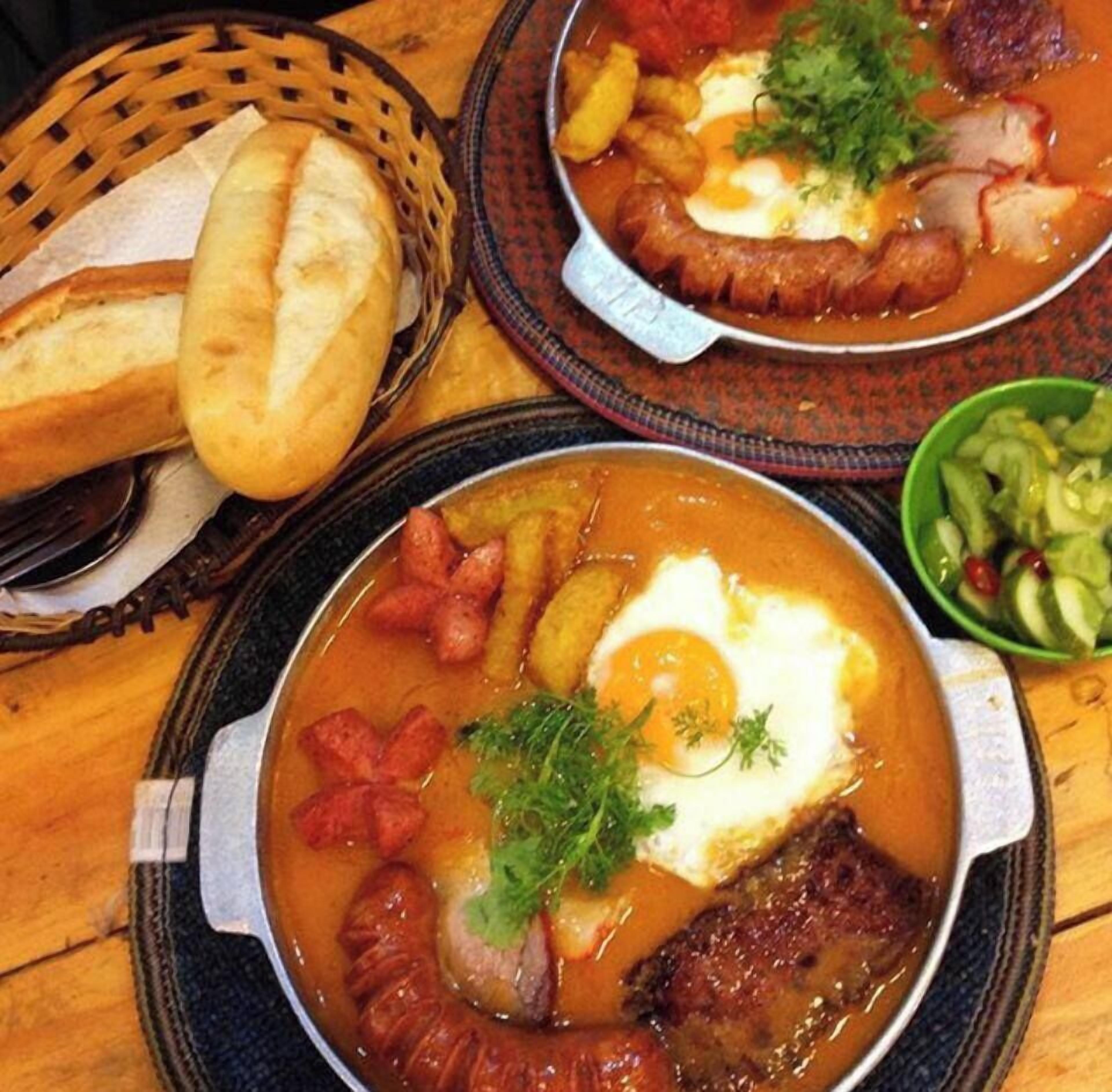 A meal with bread, a bowl of salad, and a plate with soup and eggs.