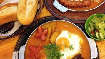 A meal with bread, a bowl of salad, and a plate with soup and eggs.