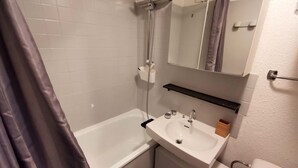 Une salle de bain avec une baignoire, un lavabo, un miroir et une douche.