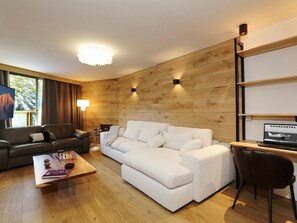 Una sala de estar moderna con una pared de madera, un sofá, una mesa de centro y un televisor.