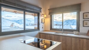 Eine moderne Küche mit einer großen Kochinsel, Holzschränken und großen Fenstern mit Blick auf die Berge.
