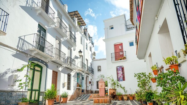 A narrow street with white buildings, balconies, and potted plants. - Casa Nobleza in C Mpeta (Còmpeta)