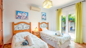 A bedroom with two beds, a ceiling fan, and a sliding glass door leading to a garden. - Casa Nobleza in C Mpeta (Còmpeta)