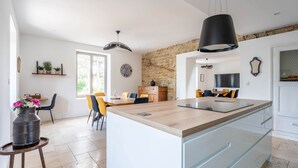 A modern kitchen with a central island, a dining area with chairs, and a stone accent wall.