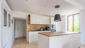 A modern kitchen with white cabinets, a wooden countertop, and a black pendant light.