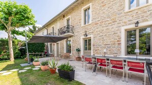A stone building with a patio, outdoor seating, and potted plants.