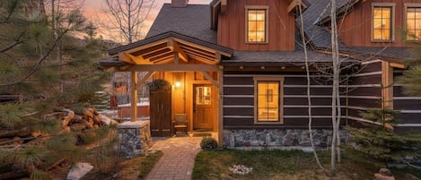 A log cabin with a stone foundation, a covered porch, and a stone pathway leading to the entrance.