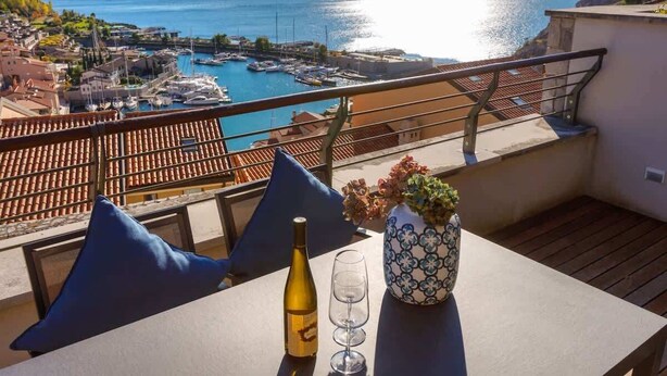 Ein Balkon mit Tisch, einer Weinflasche und einem Blumenstrauß.