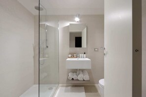 Un bagno moderno con cabina doccia in vetro, un lavandino bianco e un water.
