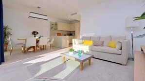 Ein modernes Wohnzimmer mit Sofa, Couchtisch und Essbereich.