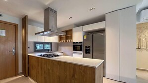 Une cuisine moderne dotée d’un îlot central, d’un four encastré et d’appareils électroménagers en acier inoxydable.