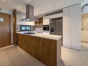 A modern kitchen with a central island, built-in oven, and stainless steel appliances.