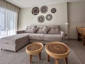 A modern living room with a grey sectional sofa, two wooden side tables, and four wall-mounted decorative plates.