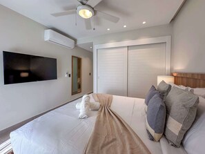A hotel room with a bed, a TV mounted on the wall, a ceiling fan, and a wardrobe.