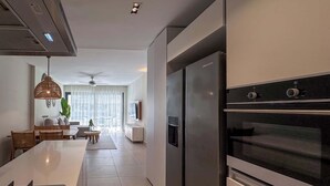 A modern kitchen with a central island, stainless steel appliances, and a dining area with a sofa and table.