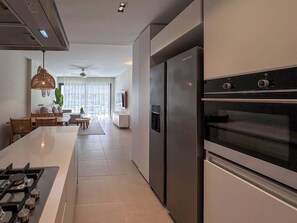 Una cocina moderna con una isla central, electrodomésticos de acero inoxidable y un comedor con sofá y mesa.