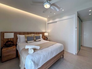 Una habitación de hotel moderna con una cama grande, cabecero de madera, lámparas de noche y un vestidor.
