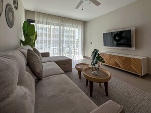Una sala de estar moderna con un sofá grande, un televisor y un mueble de madera.