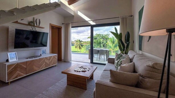 A modern living room with a flat-screen TV, wooden cabinet, and a sofa. - Stunning Penthouse located at Cocotal Golf Course (Punta Cana)