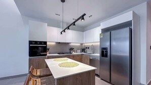 A modern kitchen with a central island, stainless steel appliances, and a wooden chair. - Stunning Penthouse located at Cocotal Golf Course (Punta Cana)